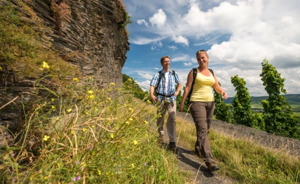 Mann und Frau in Wanderausrüstung auf einem schmalen Wanderweg