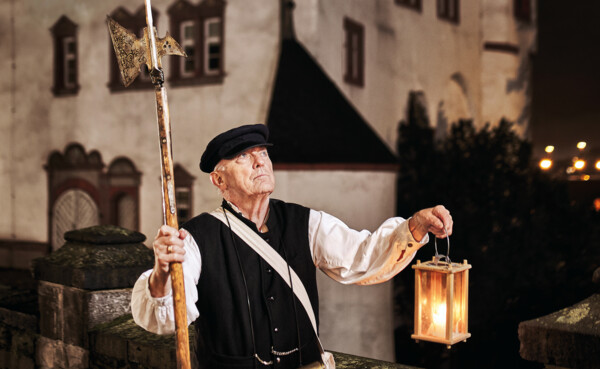 Stadtführer, bekleidet als früherer Nachtwächter, hält Laterne und Hellebarde vor der Alten Burg in Koblenz ©Koblenz-Touristik GmbH, Picture Colada