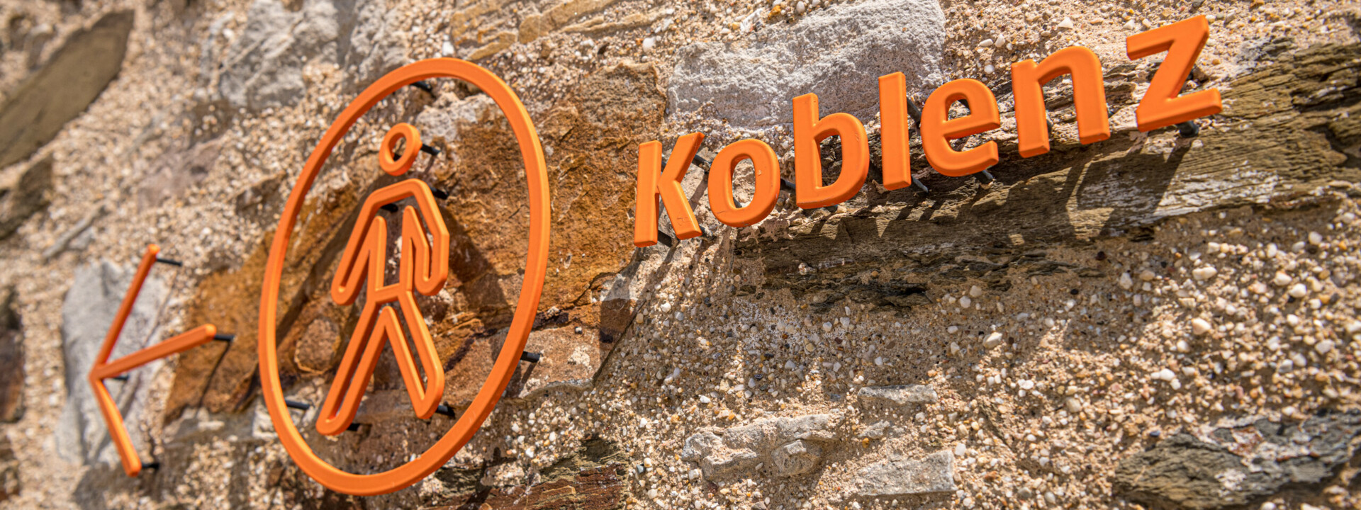 Koblenzschild an Mauer mit Pfeil in Richtung Stadt ©Koblenz-Touristik GmbH, Dominik Ketz