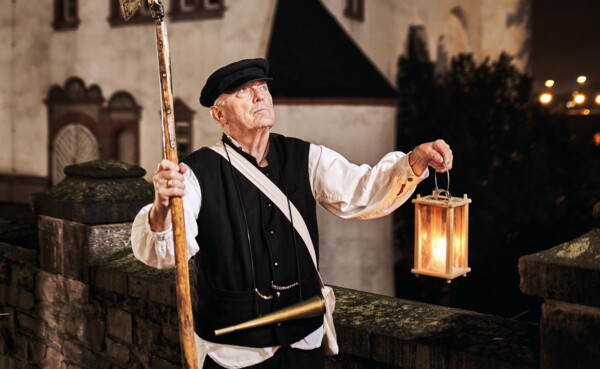 Stadtführer, bekleidet als früherer Nachtwächter, hält Laterne und Hellebarde vor der Alten Burg in Koblenz © Koblenz-Touristik GmbH, Picture Colada