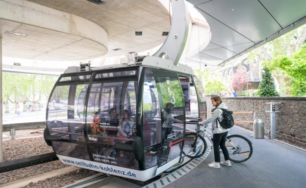 Fahrradfahrerin steigt mit ihrem Fahrrad in die Seilbahn ein