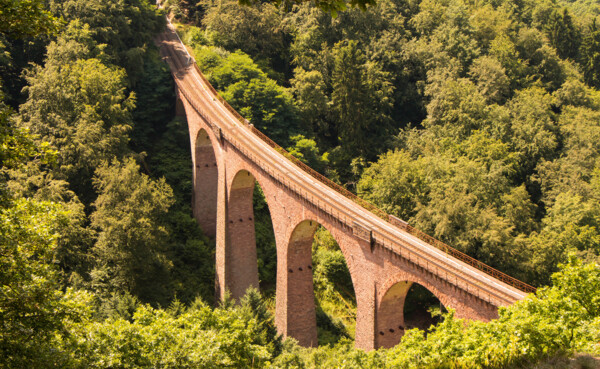 Viadukt aus rotem Backstein, der sich über ein bewaldetes Tal erhebt ©klasch77 - stock.adobe.com