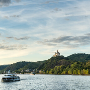 Die Marksburg sitzt auf einem Hügel über dem Rhein worauf Passagierschiffe fahren ©Dominik Ketz