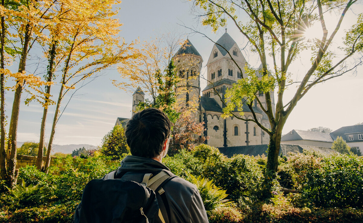 Mann von hinten blickt auf das Kloster Maria Laach im Herbst ©Koblenz-Touristik GmbH, Philip Bruederle