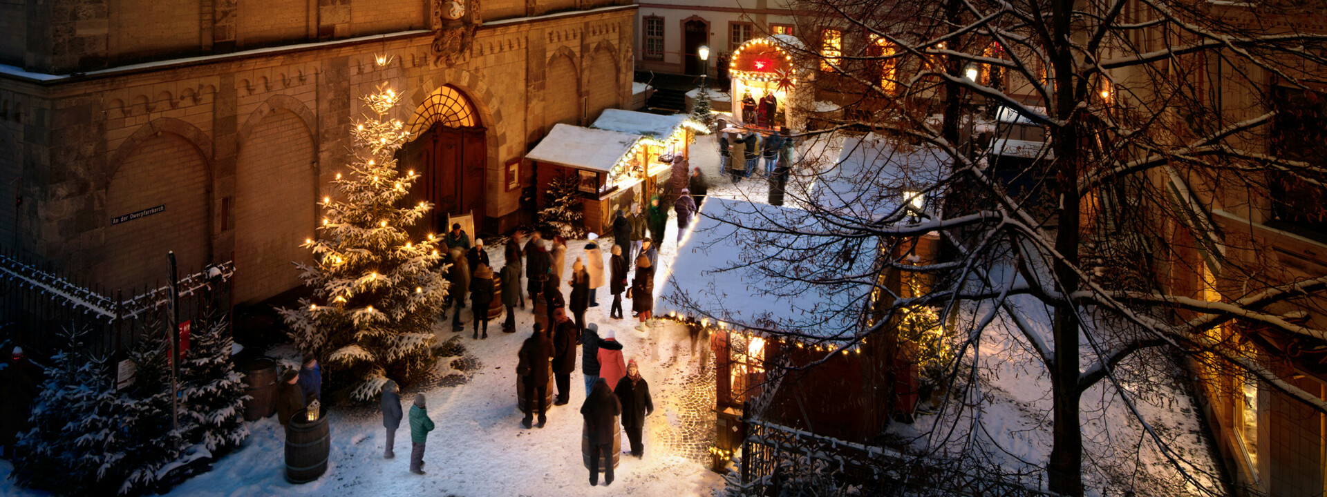 Menschen reden, essen und trinken vor beschmuckten und mit Schnee bedeckten Ständen auf dem Vorplatz der Liebfrauenkirche in Koblenz ©Koblenz-Touristik GmbH, Gauls