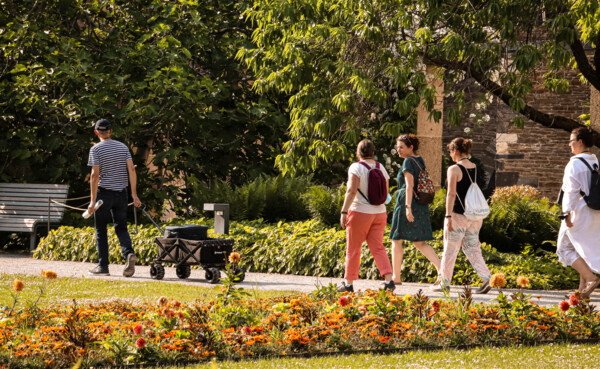 Führungsgruppe geht durch einen Garten mit Reiseführer, der Wein transportiert © Koblenz-Touristik GmbH, Johannes Bruchhof