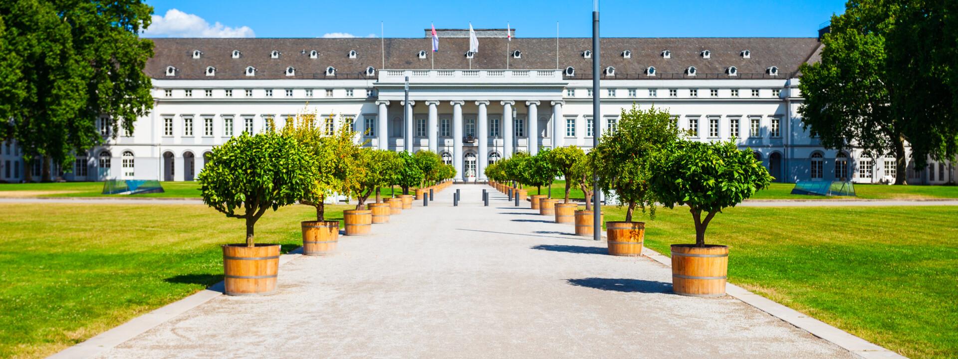 Vorderseite des Kurfürstlichen Schlosses mit Hauptweg umgeben von getopften Bäumen ©Adobe Stock, Saiko