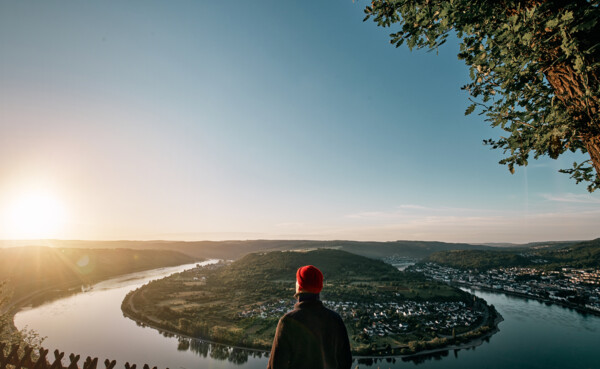 Mann blickt auf die Rheinschleife beim Sonnenaufgang ©Philip Bruederle