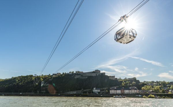 Die Seilbahn Koblenz im Gegenlicht der Sonne mit Rhein im Vordergrund und Festung Ehrenbreitstein im Hintergrund ©Koblenz-Touristik GmbH, Dominik Ketz