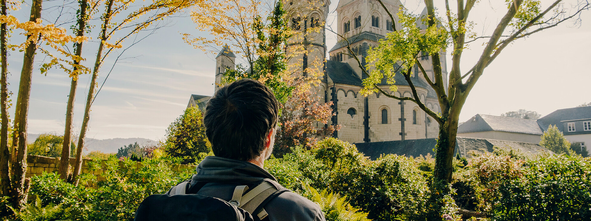 Mann von hinten blickt auf das Kloster Maria Laach im Herbst ©Koblenz-Touristik GmbH, Philip Bruederle