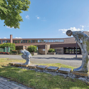 Gebäude des Keramikmuseums Westerwald von außen, davor Grünstreifen mit zwei Figuren  © Matthias Brand