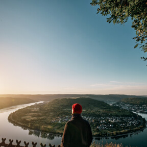 Mann blickt auf die Rheinschleife beim Sonnenaufgang ©Philip Bruederle