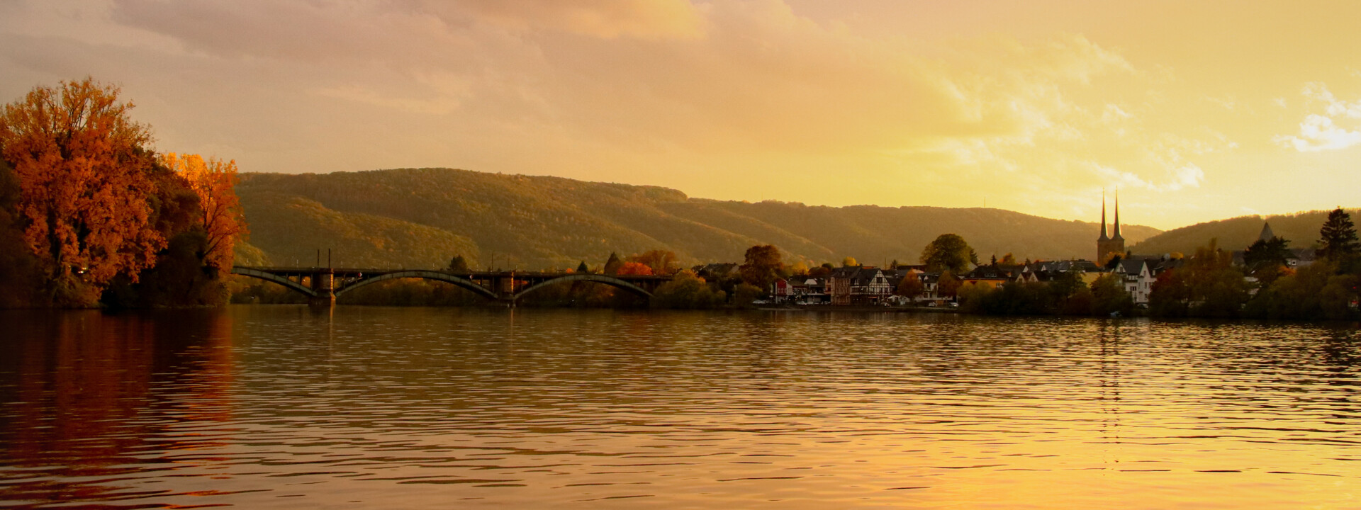 Blick über die Mosel bei Sonnenuntergang, im Hintergrund ein kleiner Ort mit Kirchturmspitze ©Johannes Bruchhof