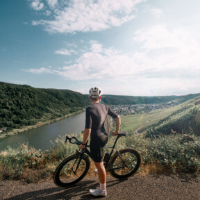 Man sieht einen Mountainbike-Fahrer von hinten, der in die Ferne auf die Mosel und die Weinberge blickt © Koblenz-Touristik GmbH, Philip Bruederle