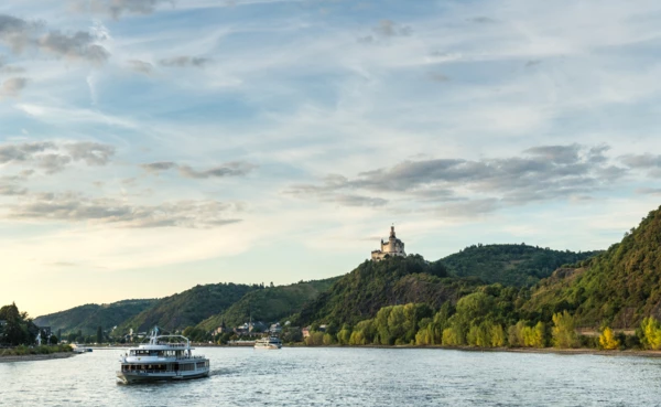 Die Marksburg sitzt auf einem Hügel über dem Rhein worauf Passagierschiffe fahren