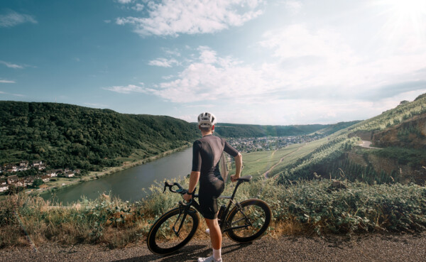 Man sieht einen Mountainbike-Fahrer von hinten, der in die Ferne auf die Mosel und die Weinberge blickt © Koblenz-Touristik GmbH, Philip Bruederle