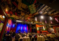 Menschen sitzen an bedeckten Tischen vor einer B&uuml;hne in Vorbereitung auf eine Show in Caf&eacute; Hahn &copy; Caf&eacute; Hahn