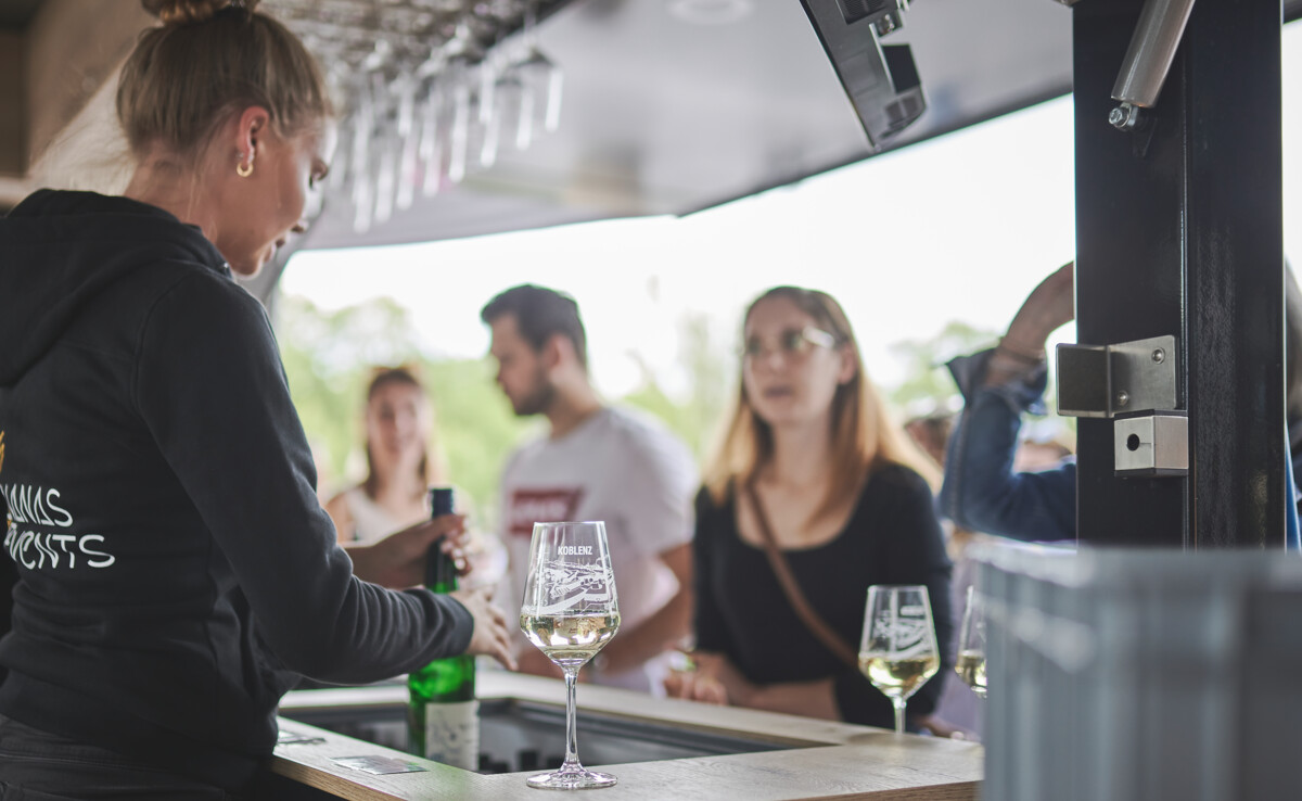 Ein Glas Wein steht auf der Weintheke und Kunden bestellen ©Koblenz-Touristik GmbH, Picture Colada