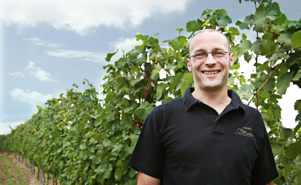Winzer Johannes Müller lächelt für die Kamera in seinem Weinberg