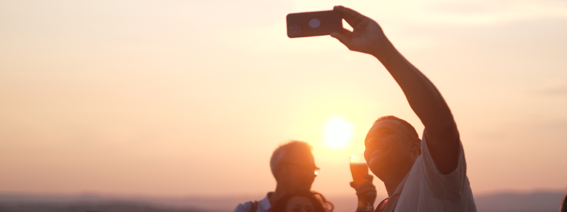 Mann macht von sich ein Selfie, im Hintergrund Sonnenuntergang  ©PlusPunktFilm