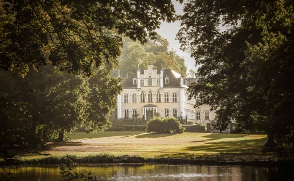 Schloss Sayn steht zwischen öppigen Bäumen hinter einem Weiher