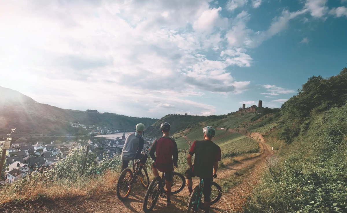 Freundesgruppe auf Mountainbikes auf einem Radweg neben der Mosel mit Burg Thurant im Hintergrund &copy; Philip Bruederle - Koblenz-Touristik GmbH