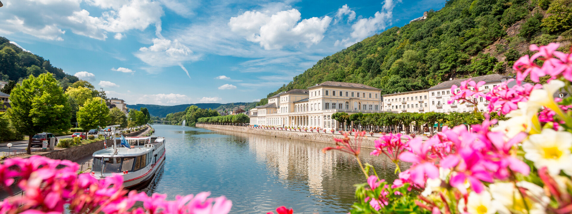 Pinke Blumen bluten vor der Lahn mit romantischen Gebäuden und einem kleinen Schiff im Hintergrund © Pinke Blumen bluten vor der Lahn mit romantischen Gebäuden und einem kleinen Schiff im Hintergrund ©