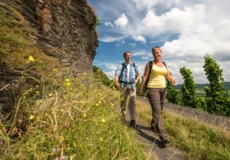 Mann und Frau in Wanderausrüstung auf einem schmalen Wanderweg