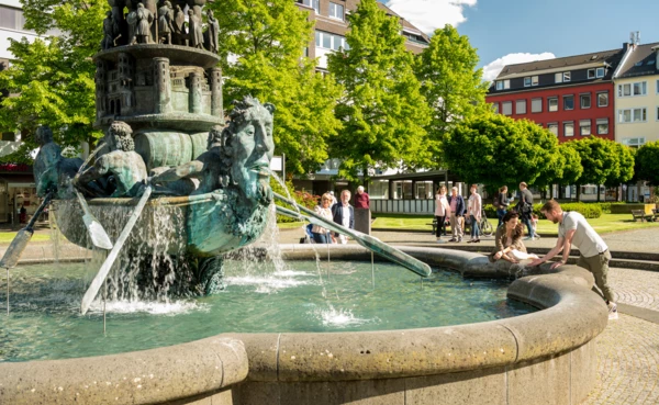 Brunnen "Historiensäule" auf dem Görresplatz in Koblenz umgeben von kleinen Menschengruppen
