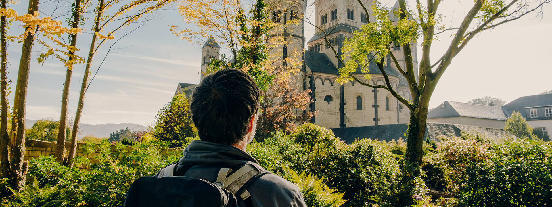 Mann von hinten blickt auf das Kloster Maria Laach im Herbst ©Koblenz-Touristik GmbH, Philip Bruederle