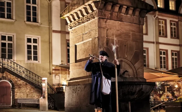 Ein Stadtf&uuml;hrer verkleidet als Nachtw&auml;chter steht vor einem Brunnen in der Altstadt &copy; 