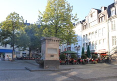 © Koblenz-Touristik GmbH Brunnen auf dem Platz "Am Plan" in Koblenz mit Cafés und Bäumen im Hintergrund © Koblenz-Touristik GmbH