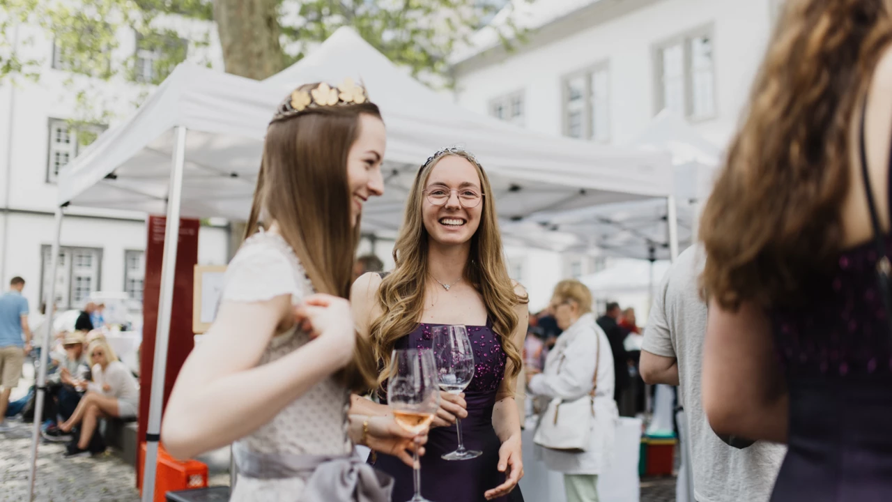 Weinköniginnen lachen mit Weingläsern in den Händen bei einem Weinfest am Rathausplatz in Koblenz