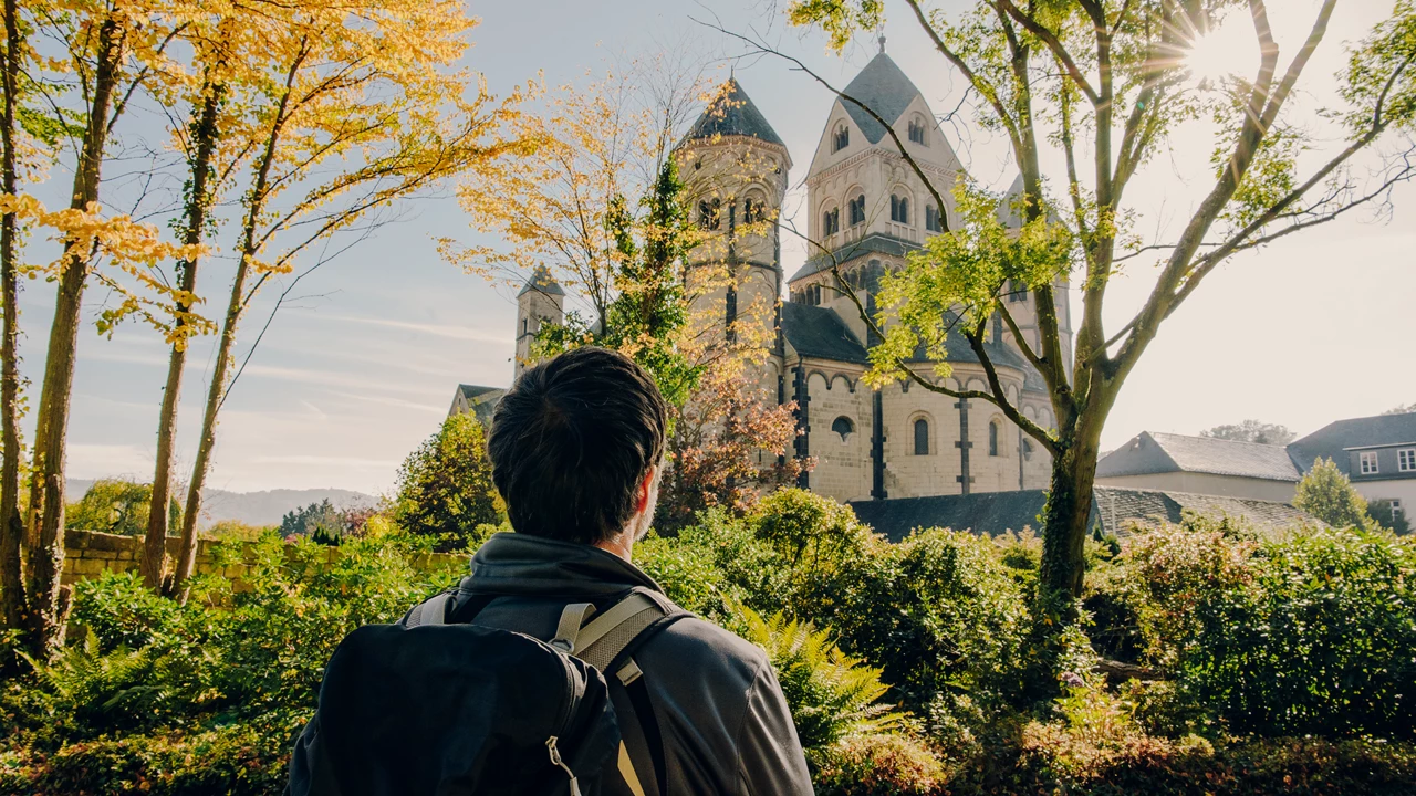 Man von Hinten blickt auf das Kloster Maria Laach im Herbst