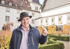 Lächelnder Stadtführer mit einem Glas Wein in der Hand steht vor dem Basilika St. Kastor im Herbst © Lächelnder Stadtführer mit einem Glas Wein in der Hand steht vor dem Basilika St. Kastor im Herbst ©