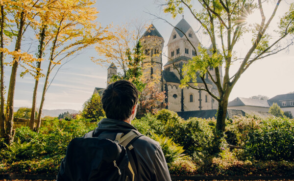 Mann von hinten blickt auf das Kloster Maria Laach im Herbst ©Koblenz-Touristik GmbH, Philip Bruederle