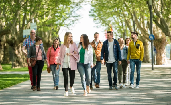 Reisegruppe spaziert auf dem Fußweg der Rheinanlagen in Koblenz