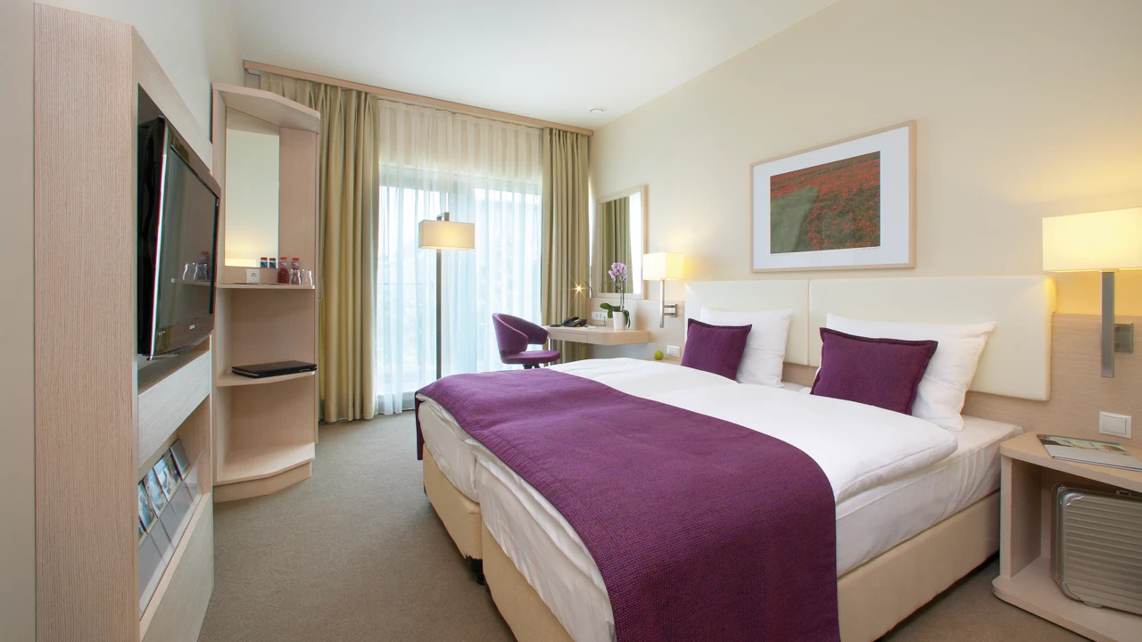 Hotelzimmer mit Teppichboden, Bodenfenster und Fernseher