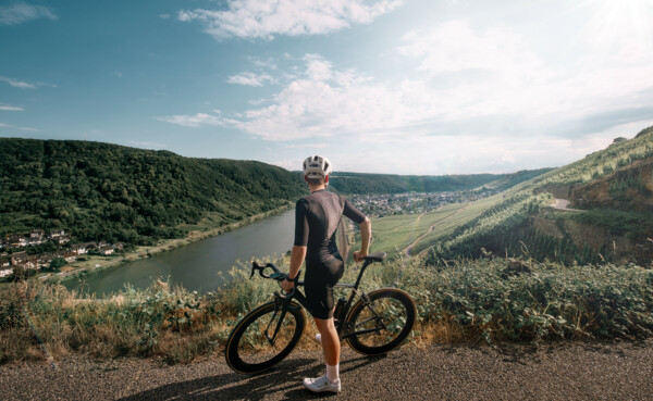 Man sieht einen Mountainbike-Fahrer von hinten, der in die Ferne auf die Mosel und die Weinberge blickt ©Koblenz-Touristik GmbH, Philip Bruederle