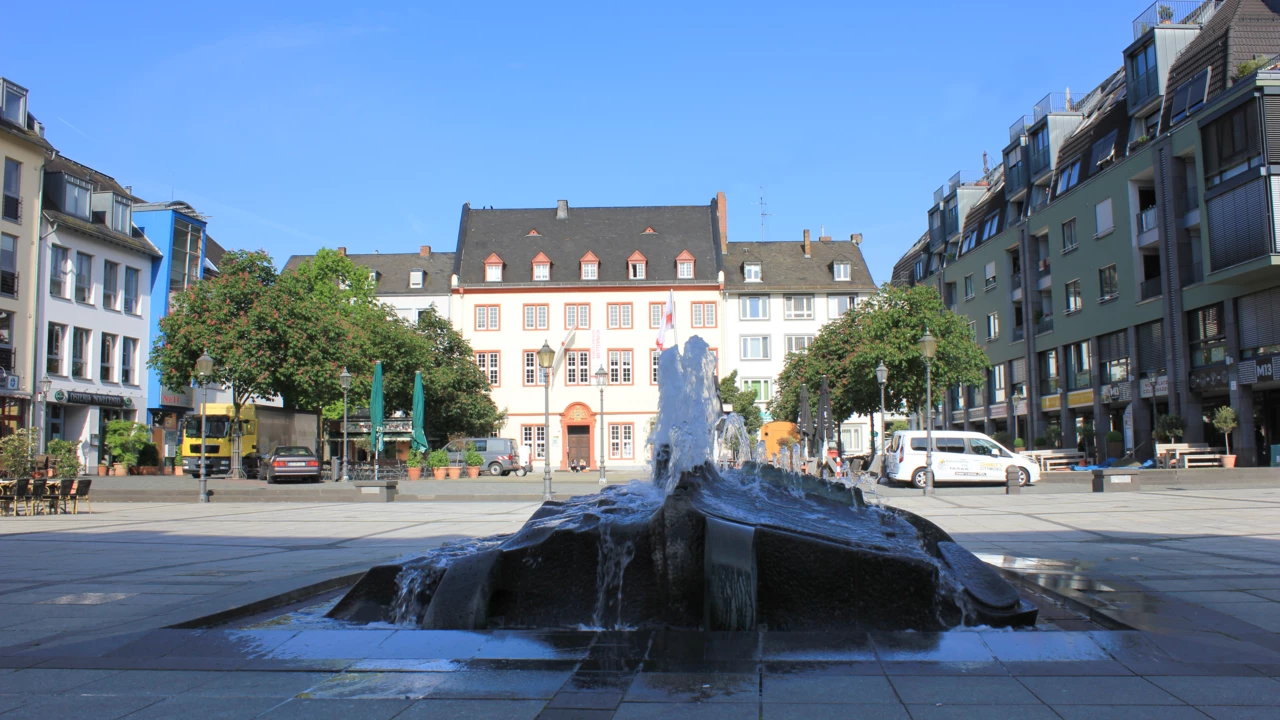 Brunnen auf dem Münzplatz mit Haus Metternich und Geschäfte im Hintergrund