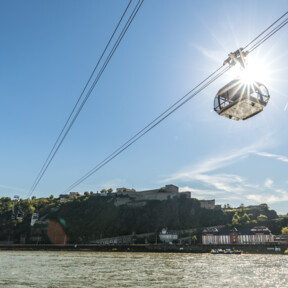 Die Seilbahn Koblenz im Gegenlicht der Sonne mit Rhein im Vordergrund und Festung Ehrenbreitstein im Hintergrund ©Koblenz-Touristik GmbH, Dominik Ketz