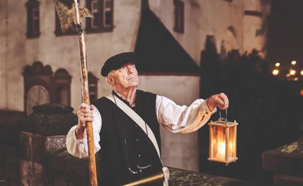 Stadtführer, bekleidet als früherer Nachtwächter, hält Laterne und Hellebarde vor der Alten Burg in Koblenz © Koblenz-Touristik GmbH, Picture Colada