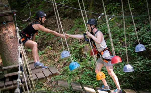 Zwei Teenager mit Kletterausrüstung balancieren auf einem Kletterparcours