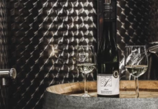 Zwei Weingläser mit Riesling stehen auf einem Fass neben einer Weinflasche
