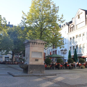 Brunnen auf dem Platz "Am Plan" in Koblenz mit Cafés und Bäumen im Hintergrund ©Koblenz-Touristik GmbH