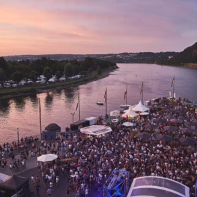 Blick von oben auf das Deutsche Eck bei Abendd&auml;mmerung w&auml;hrend einer Veranstaltung, Menschengruppen stehen vor einer B&uuml;hne und an St&auml;nden verteilt auf dem Gel&auml;nde &copy; Picture Colada