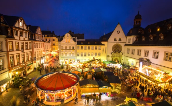 Blick auf den erleuchteten Jesuitenplatz mit Weihnachtsmarktbuden und Kinderkarussell