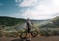 Man sieht einen Mountainbike-Fahrer von hinten, der in die Ferne auf die Mosel und die Weinberge blickt