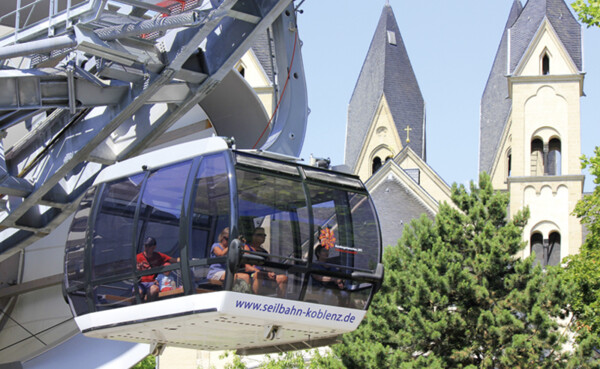 Kabine der Seilbahn Koblenz mit Passagieren. Türme der Basilika St. Kastor im Hintergrund ©Koblenz-Touristik GmbH