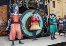 Drei kostümierte Pantomimenspieler auf dem Gauklerfest stehen vor einer großen Uhr und schauen ins Publikum. © © GDKE, Ulrich Pfeuffer